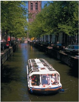 A canal boat in a narrow canal in the Netherlands. (Reproduced by permission of Photo Researchers, Inc.)