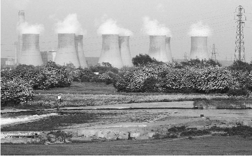 Giant cooling towers dominate the landscape near a nuclear power plant. Although nuclear fission is an efficient energy source, it produces radioactive waste.